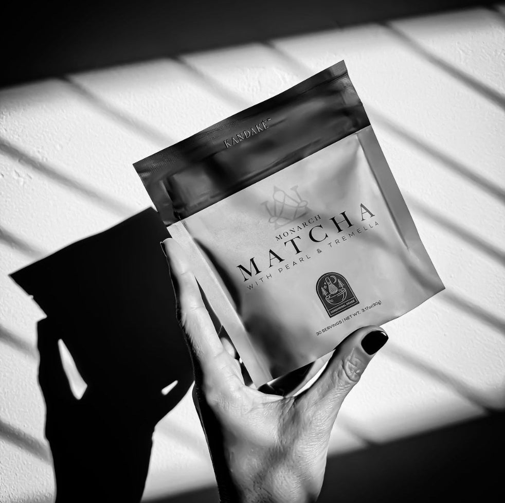 Hand holding a package of 'Matcha' tea with a sunlit background