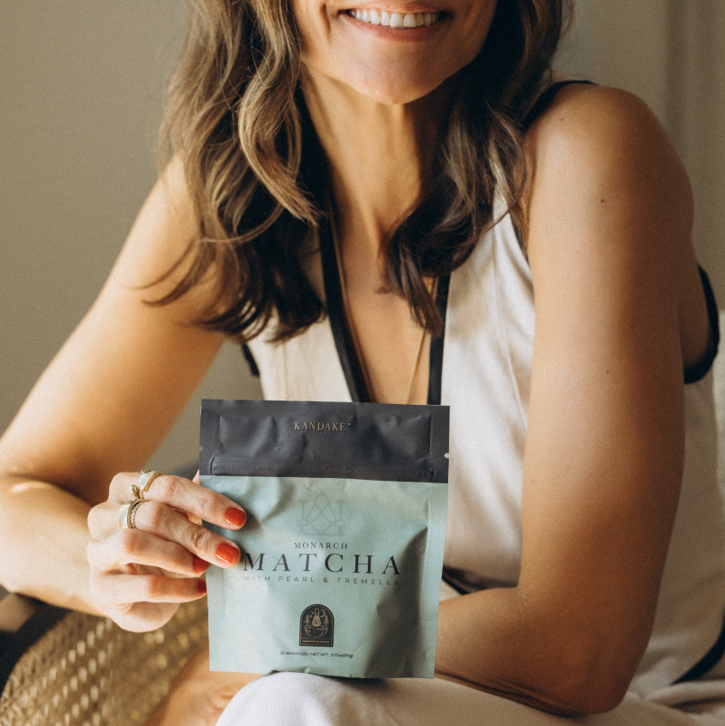 Candice Barley holding a package of Monarch Matcha powder with a neutral background